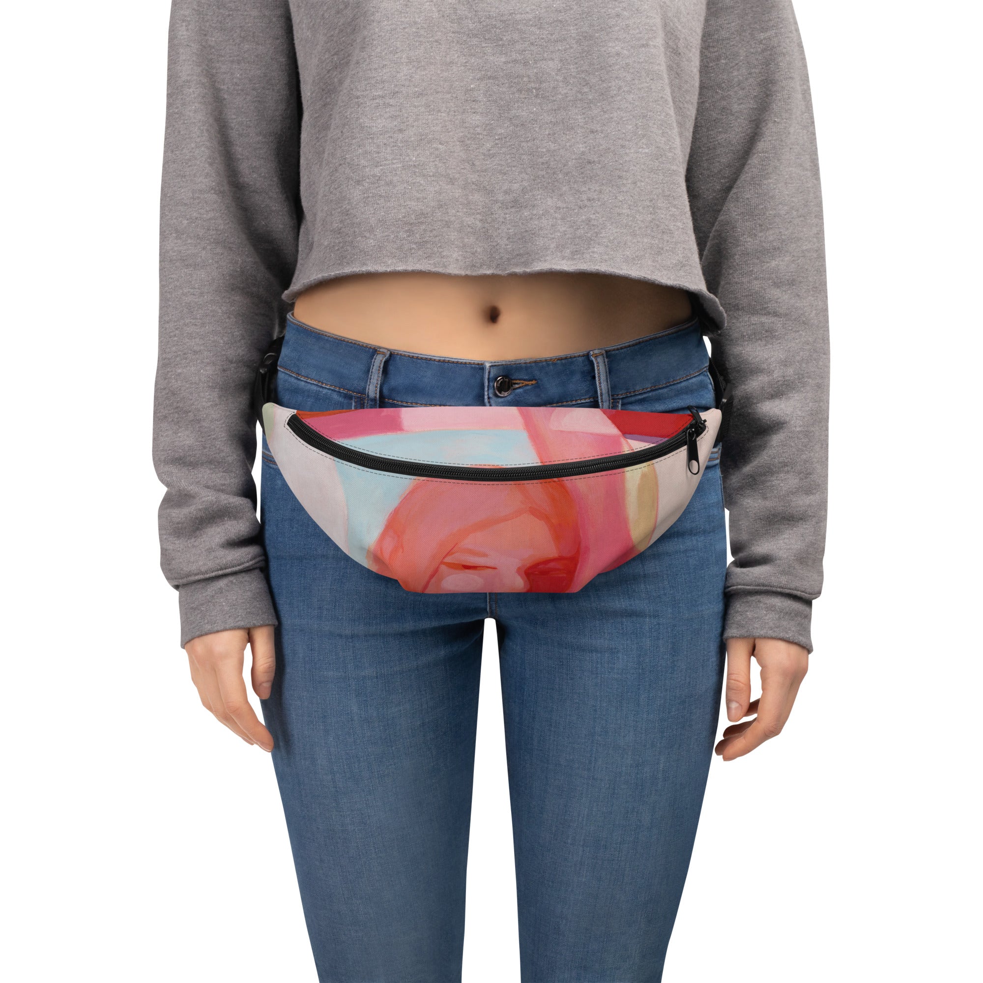 Person in a grey top and jeans wearing the "Being Human" belt bag with a pink and coral art print around the waist.

